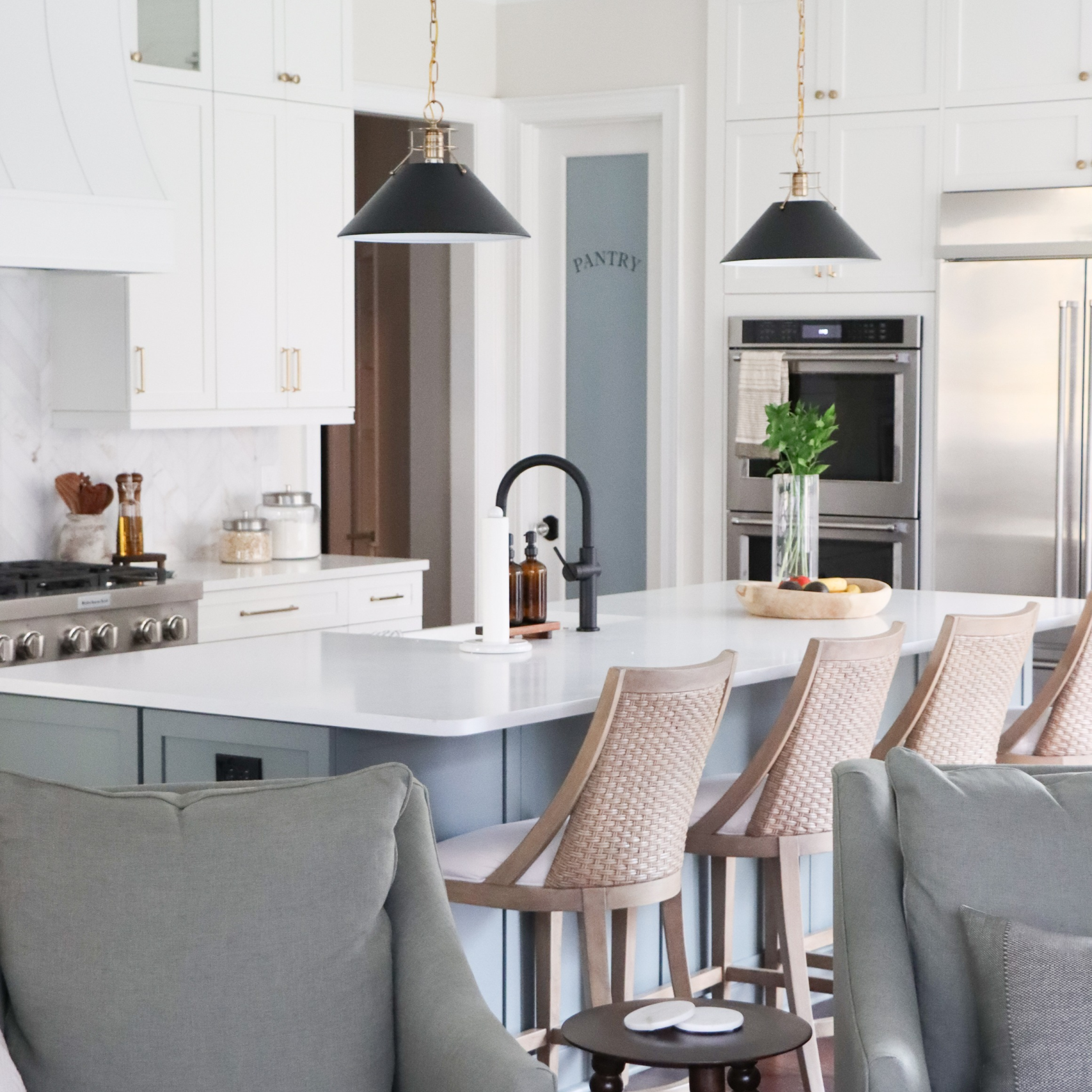 looking into modern kitchen with three counter chairs and blue cabinets